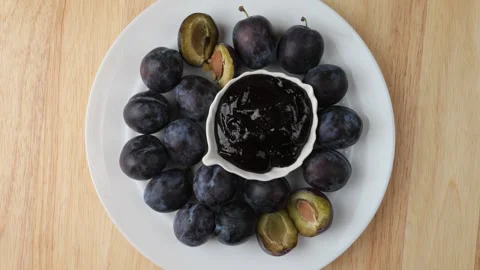 Fresh plums and homemade jam rotating on a white plate Stock Footage 342437798