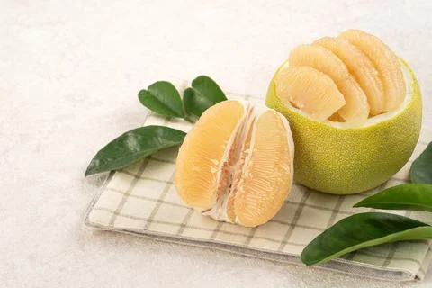 Fresh pomelo fruit with leaf on white table background. Stock Photos
