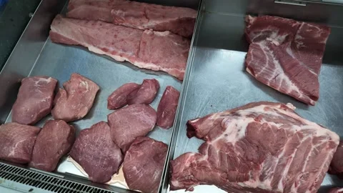 Fresh pork cuts displayed on a stainless steel counter in a local butchery shop. Video stock 341401442