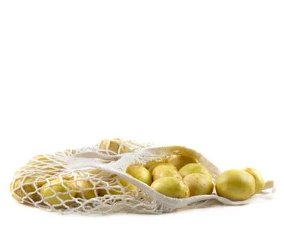 Fresh potatoes in a string bag on a white background. Stock Photos
