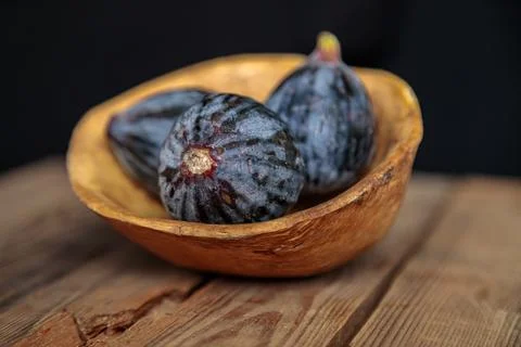 Fresh purple figs in a bowl on a wooden background from old boards. Stock Photos