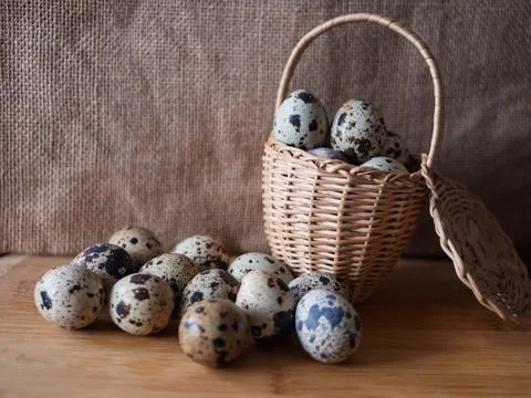Fresh Quail Eggs in a Rustic Basket on Wooden Surface Stock Photos