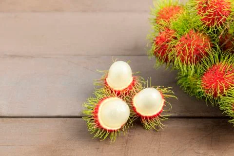 Fresh rambutan peeled on wood table with bunch of fresh ripe rambutan backgro Stock Photos