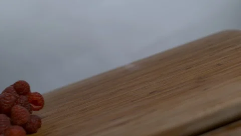 Fresh raspberries bouncing over tilt wooden surface in slow motion Stock Footage 100006563