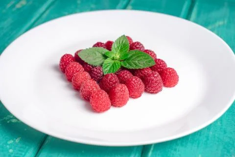 Fresh raspberries lying on a white plate on a white background Stock Photos