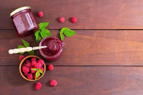 Fresh raspberry jam in a glass jar on a wooden table Stock Photos