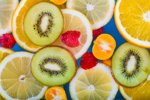 Fresh raspberry, kiwi, orange, lemon and orange slices floating in water on w Stock Photos