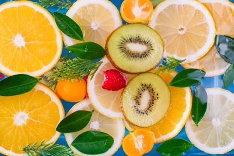 Fresh raspberry, kiwi, orange, lemon and orange slices floating in water on w Stock Photos