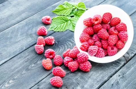 Fresh raspberry with leaves on the background of old dark boards. Selective f Stock Photos
