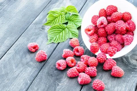Fresh raspberry with leaves on the background of old dark boards. Selective f Stock Photos