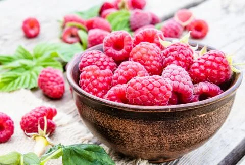 Fresh raspberry with leaves on the background of old boards. Selective focus. Stock Photos