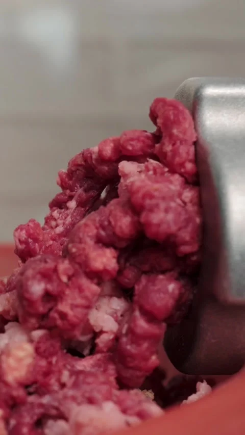 Fresh raw beef mincing continuously through electric meat grinder inside home Stock Footage 346774433