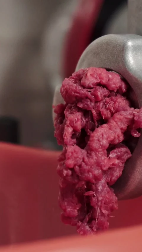 Fresh raw beef pushing steadily through metal grinder plate during butchery.. Stock Footage 348419898