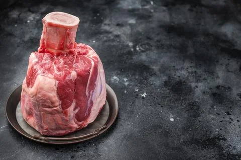 Fresh raw beef shank knuckle whole cut with bone in rustic tray on gray bac.. Stockfoto's