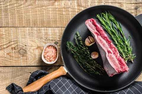 Fresh Raw beef short ribs meat on a pan with herbs. wooden background. Top view Stock Photos