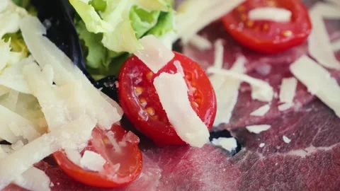 Fresh raw beef steak Carpaccio with green salad, cherry tomatoes and parmesan Stock Footage 307956706