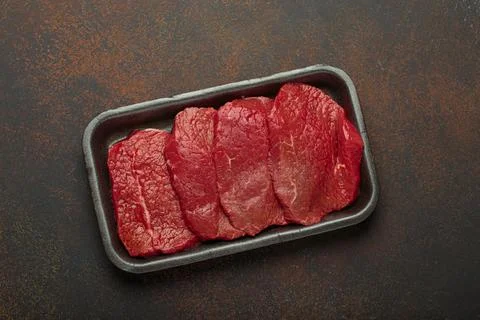 Fresh raw beef steaks lying in black plastic tray from a shop or supermarket Stock Illustration