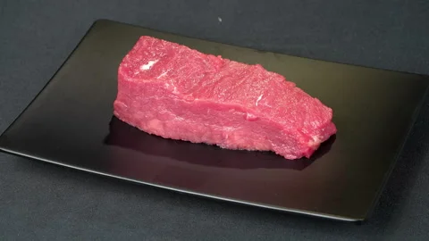 Fresh Raw Beef Tenderloin Rotating On Black Plate Stock Footage 343261016
