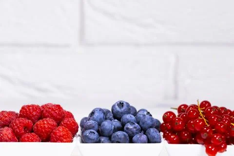 Fresh Raw Berries in white ceramic bowl on white background. Space for text. Stock Photos