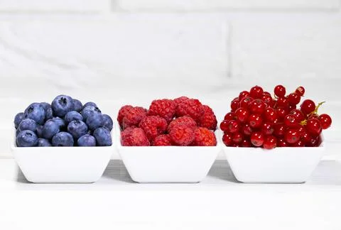 Fresh Raw Berries in white ceramic bowl on white background. Space for text. Stock Photos