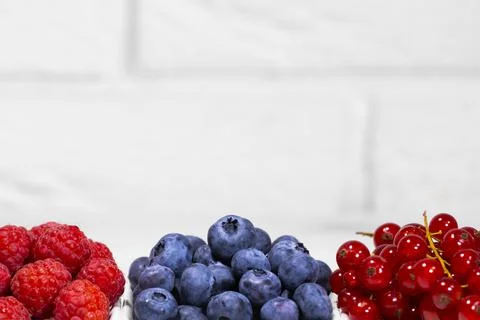 Fresh Raw Berries in white ceramic bowl on white background. Space for text. Stock Photos