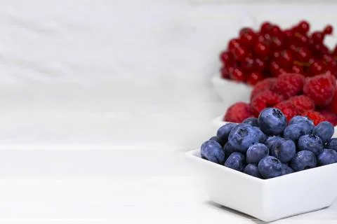 Fresh Raw Berries in white ceramic bowl on white background. Space for text Stock Photos