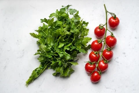 Fresh raw cherry tomatoes with bunch of parsley on a marble - free background Stock Photos
