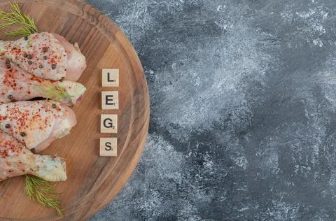 Fresh raw chicken legs with Cube letters on wooden board Stock Photos