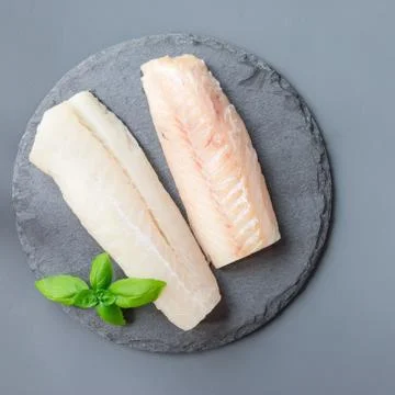 Fresh raw cod fillet with basil on a stone plate, top view, square 스톡 사진