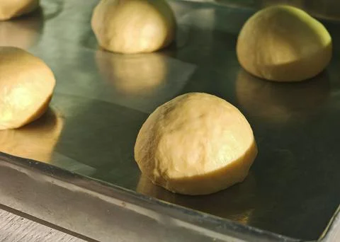 Fresh raw dough balls on baking tray in warm bakery light Foto stock