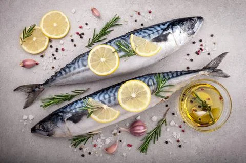 Fresh raw fish. Mackerel with salt, lemon and spices on gray background. Co.. Stock Photos