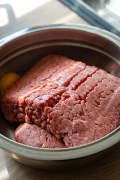 Fresh raw ground beef meat sits inside a polished metal mixing bowl ready f.. Stock Photos