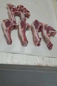 Fresh, raw lamb chops arranged neatly on a clean white surface. Stock Photos