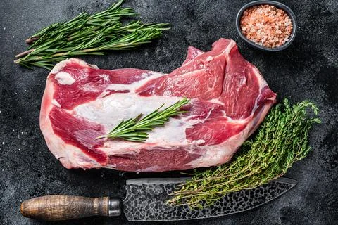 Fresh Raw lamb mutton shoulder meat with butcher knife. Black background. Top Stock Photos
