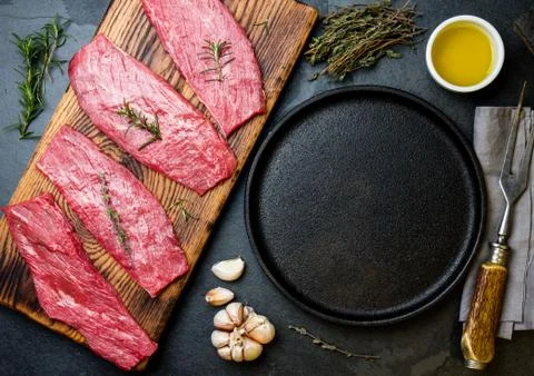 Fresh raw meat beef steaks. Beef tenderloin in cast iron pan on wooden board Stock Photos
