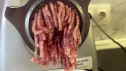 Fresh raw meat being processed through an electric meat grinder, producing .. Stockbeeldmateriaal 314621997