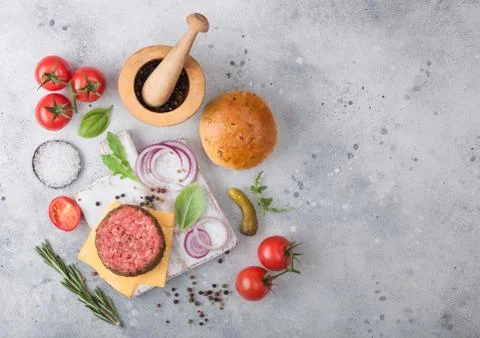 Fresh raw minced pepper beef burger on vintage chopping board with buns Stock Photos