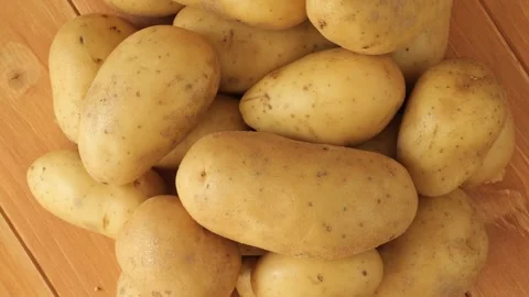 Fresh raw organic potatoes rotating on wooden background Stock Footage 340160143