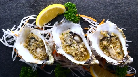 Fresh Raw Oysters in Shells with Lemon and Fried Garlic on Black Textured Slate Stock Footage 138165350