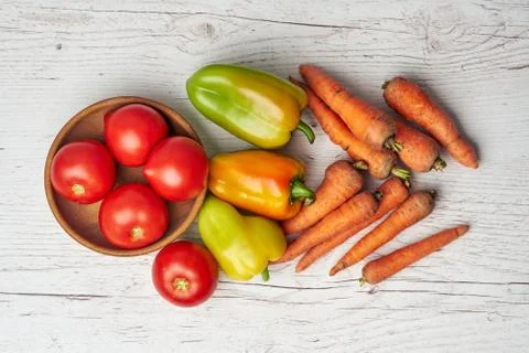 Fresh raw peppers, carrots and tomatoes in wooden bowl on wooden background Stock Photos