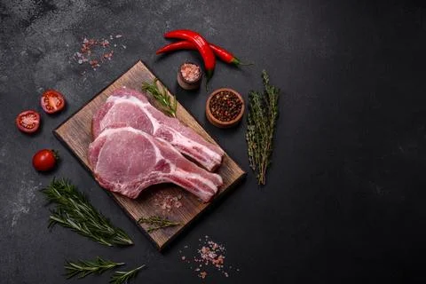 Fresh raw pork meat on the ribs with spices and herbs on a wooden cutting boa Stock Photos