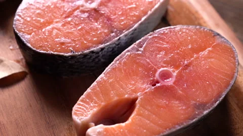 Fresh raw salmon fish steak with herbs and vegetables on wooden background Video stock 145676799