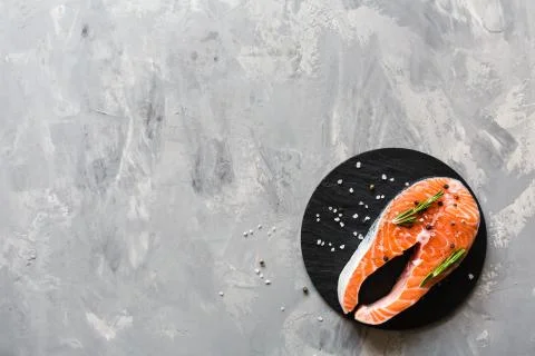 Fresh raw salmon fish steak with spices on dark stone background. Creative Foto stock