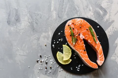Fresh raw salmon fish steak with spices on dark stone background. Creative la Foto stock