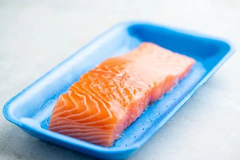 Fresh raw salmon in plastic container, close up view. Stock Photos