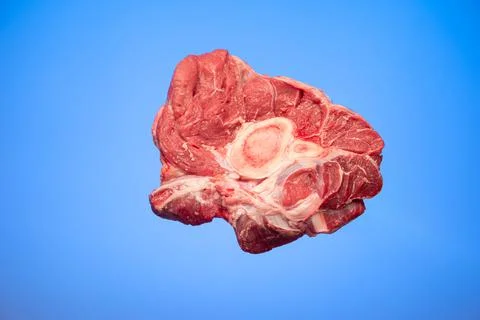 Fresh raw slice of red beef shank isolated on blue background studio shot Fotos de archivo
