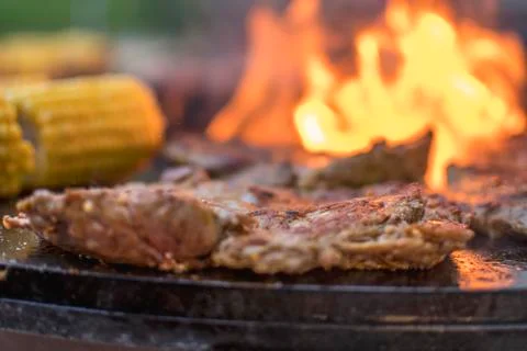 Fresh raw steak with corn an a open fire grill Stock Photos