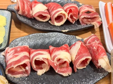 Fresh Raw Thinly Sliced Beef Rolls on Black Stone Plate Hotpot Shabu-Shabu Stock Photos