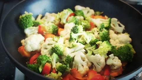 Fresh raw veggies vegetable cooking on an iron pan. Healthy homemade vegan meal Stock-Footage 136811322
