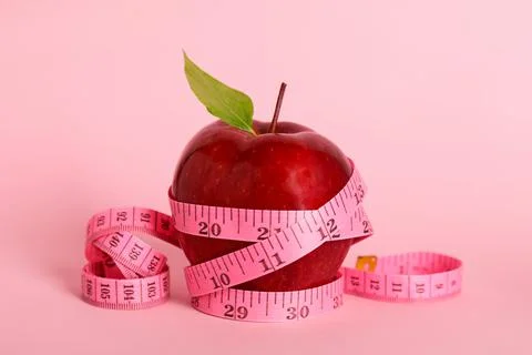 Fresh red apple with measuring tape on pink background Stock Photos